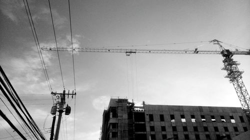 Low angle view of electricity pylon in city against sky