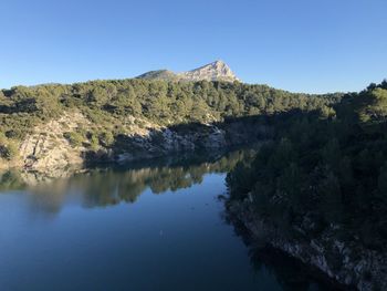 Scenic view of lake and mountains against clear blue sky