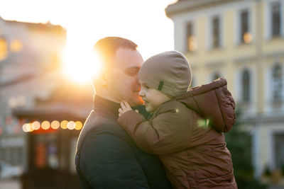 A happy father and three year old son hug in a city street. warm relationships between parents 