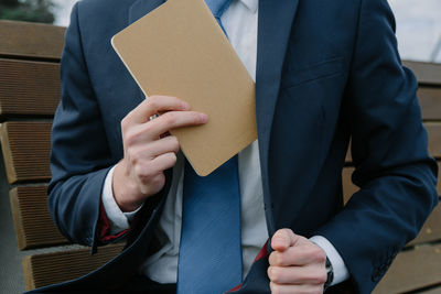 Midsection of businessman putting book in blazer