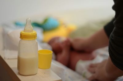 Close-up of milk bottle by mother and baby