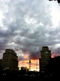 Low angle view of skyscrapers against cloudy sky