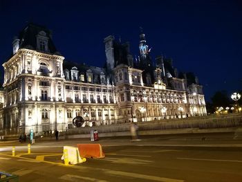 Illuminated city buildings against sky at night