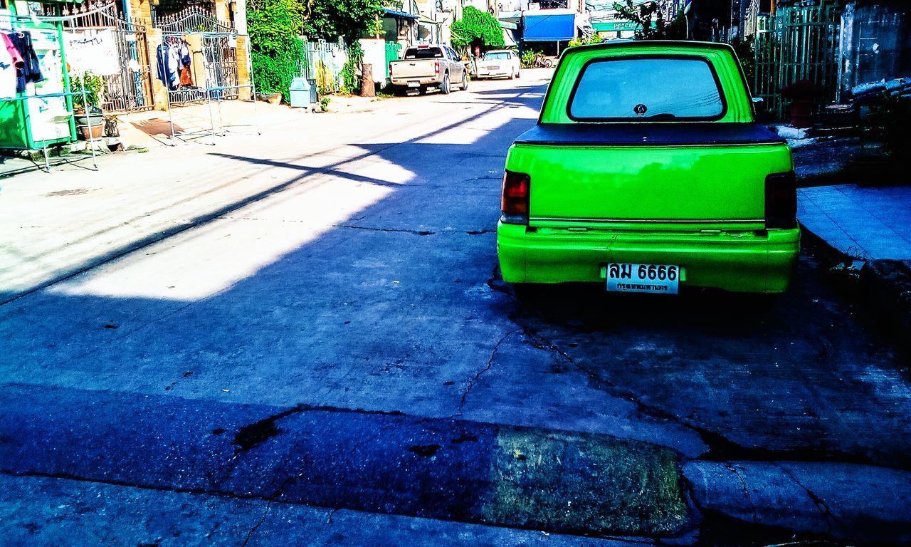 transportation, city, mode of transportation, car, street, architecture, motor vehicle, land vehicle, road, day, sunlight, built structure, no people, text, shadow, sign, communication, outdoors, nature, place