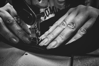 Cropped hands sewing textile on machine