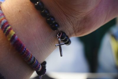 Cropped hand wearing bracelet with cross