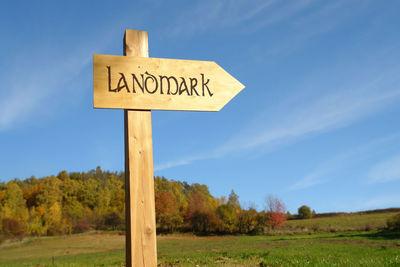 Information sign on field against sky