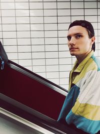 Portrait of young man standing on escalator