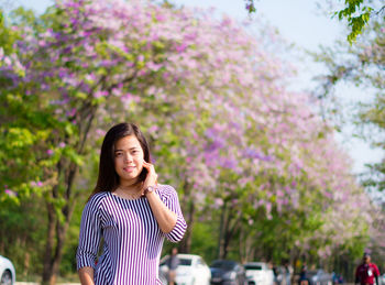 Young woman standing on purple flowering tree