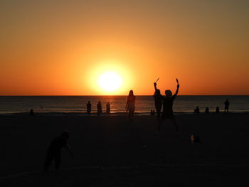 Silhouette people on beach against sky during sunset