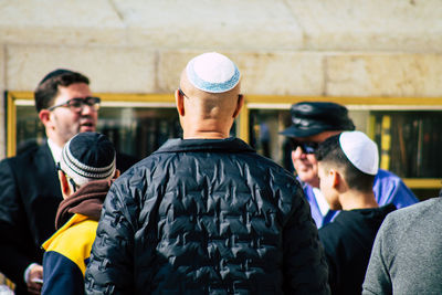 Rear view of men standing against wall