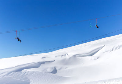 Low angle view of people on snowcapped mountain against sky