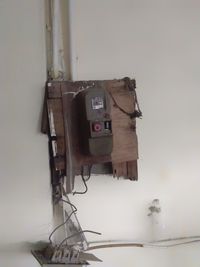 Close-up of old telephone booth against wall