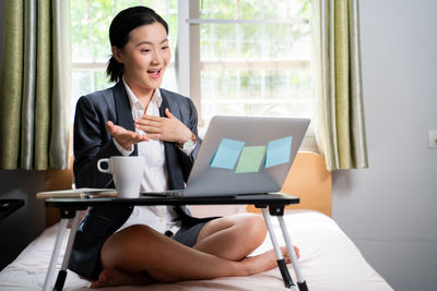 Mid adult woman using mobile phone while sitting on table