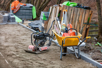 Construction yellow wheelbarrow, petrol vibrating plate and the necessary tool.