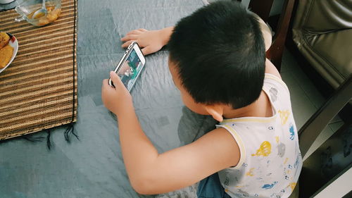 High angle view of boy using mobile phone at home