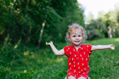 Cute girl with arms outstretched standing against plants