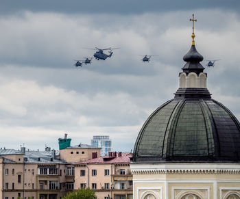 Military helicopters flying over buildings in city