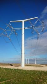 Electricity pylon on field against blue sky