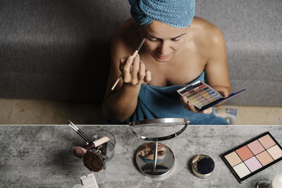 Young woman using mobile phone while sitting on table