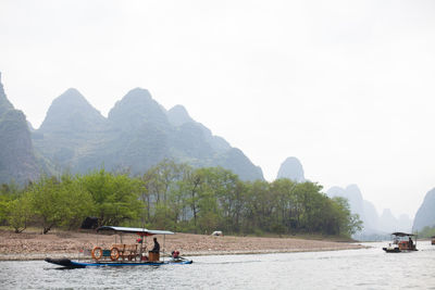 Tourboats on li river against mountains and clear sky