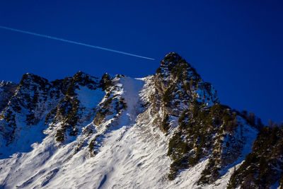 Low angle view of snowcapped mountain against blue sky