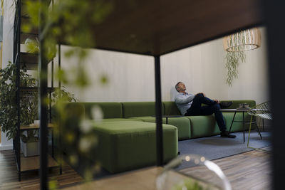 Businessman relaxing while sitting on sofa at office