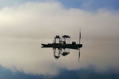 Crane on sea against sky during sunset