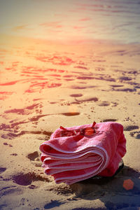 Close-up of pink umbrella on beach against sky during sunset