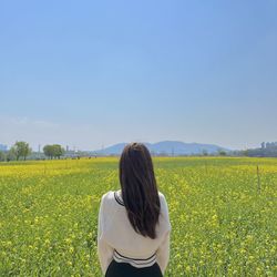 Rear view of woman standing on field against clear sky