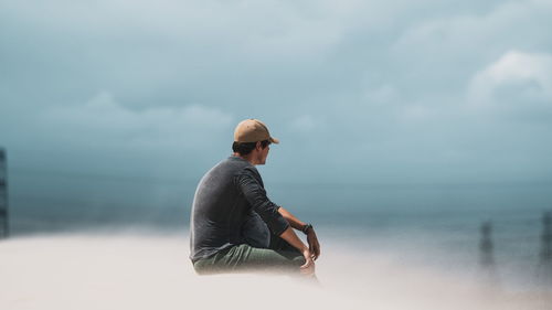 Side view of man looking at sea against sky