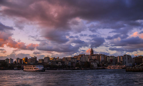 View of city at waterfront against cloudy sky