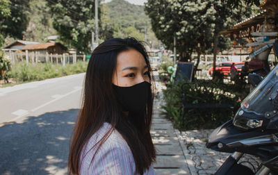 Portrait of young woman standing on road in city