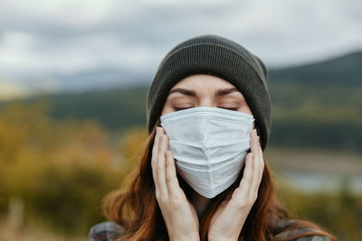 Portrait of young woman holding covering face