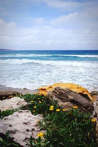 Scenic view of sea and rocks against cloudy sky