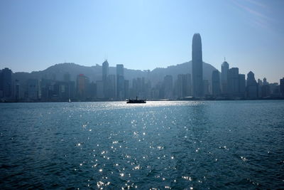 View of city at waterfront against blue sky