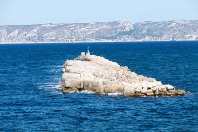 Rock formation in sea against blue sky