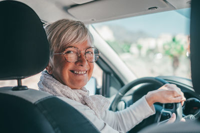 Happy senior woman sitting in car