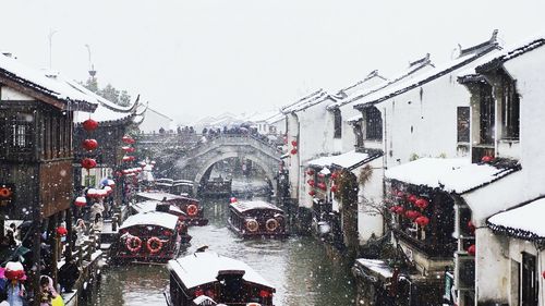 Cars on snow covered city against sky