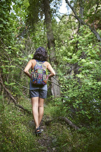 Young girl walking in the woods. she has a backpack on her back.