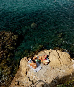 High angle view of people sitting on rock by sea