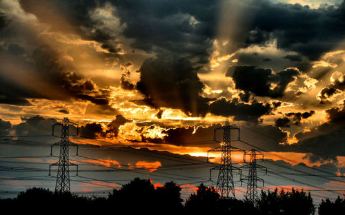 Low angle view of silhouette electricity pylon against sky during sunset