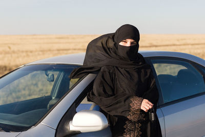 Brunette muslim woman in the reflection of the car mirror in the salon.