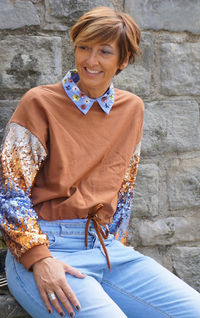 Portrait of a smiling young woman sitting against wall