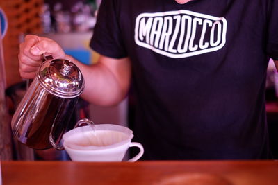 Midsection of man pouring coffee cup