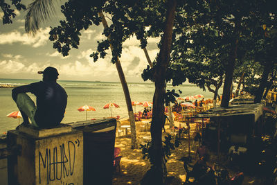 Man standing by tree against sea