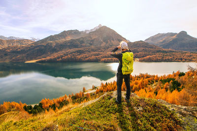 Rear view of woman standing on mountain against sky