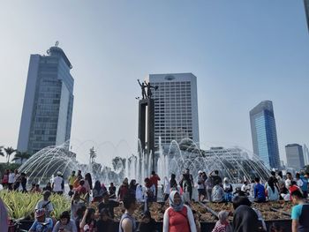 People on city buildings against clear sky