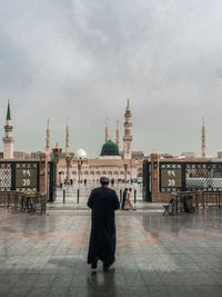 Rear view of man standing outside temple against sky