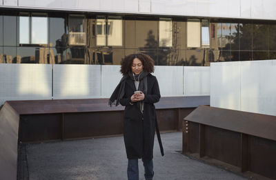 Beautiful woman with smartphone in front of office building